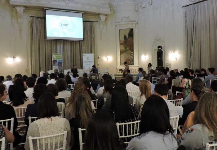 Se ve un salón lleno de público de espaldas a la imagen y que miran hacia un living donde están dialogando los directores nacionales de Ordenamiento Territorial José Freitas y de Vivienda Salvaros Schelotto