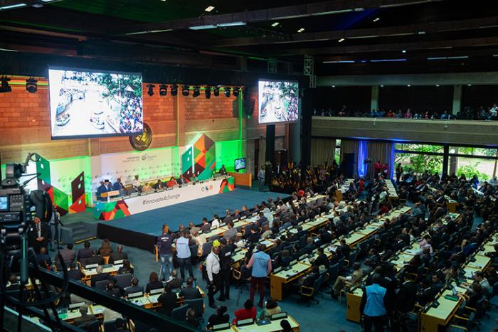 Asamblea ONU-Habitat Asamblea de ONU Habitat. Sala grande de dos niveles con pantallas, donde participan representantes de distintas instituciones del mundo vinculadas al medio ambiente