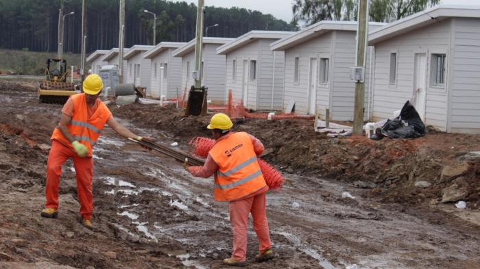 dos obreros trabajando frete a varias viviendas
