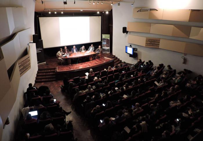 Sala de Actos en la Facultad de Arquitectura donde autoridades del Mvotma realizan la apertura de la actividad ante los y las asistentes. La sala se encuentra con la capacidad completa