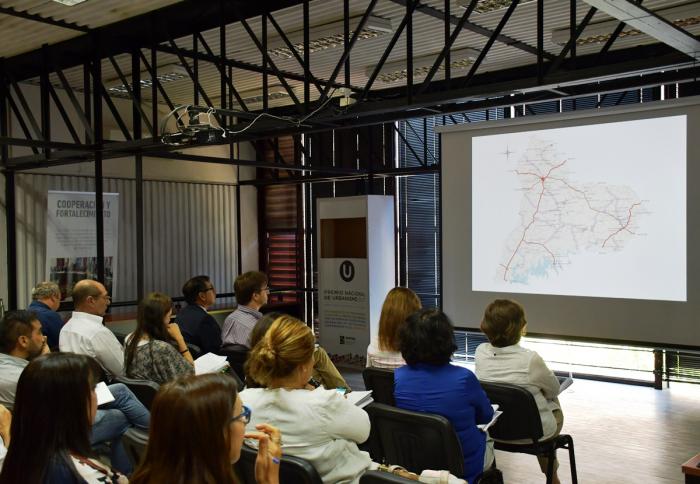 Presentación Plan Paso de los Toros En sala de reuniones de Dinot se encuentran el director nacional entrante Norbertino Suárez y el saliente José Freitas y más funcionarios de la Dinot sentados frente a una pantalla gigiante donde se observa un mapa, parte del contenido del Plan.