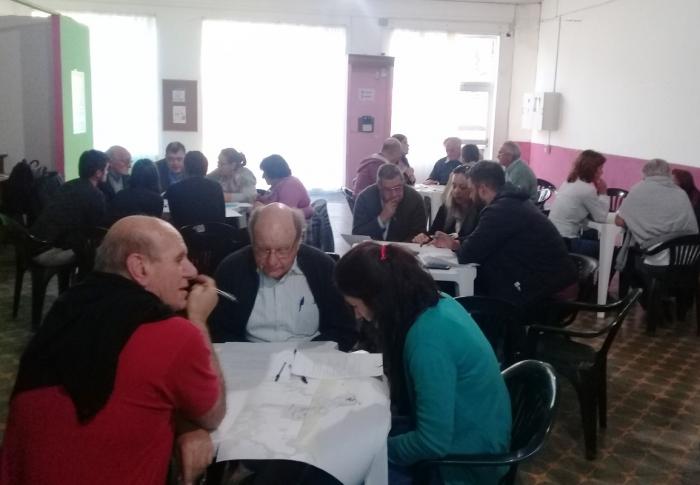 Varias mesas con personas sentadas trabajando en subgrupos 