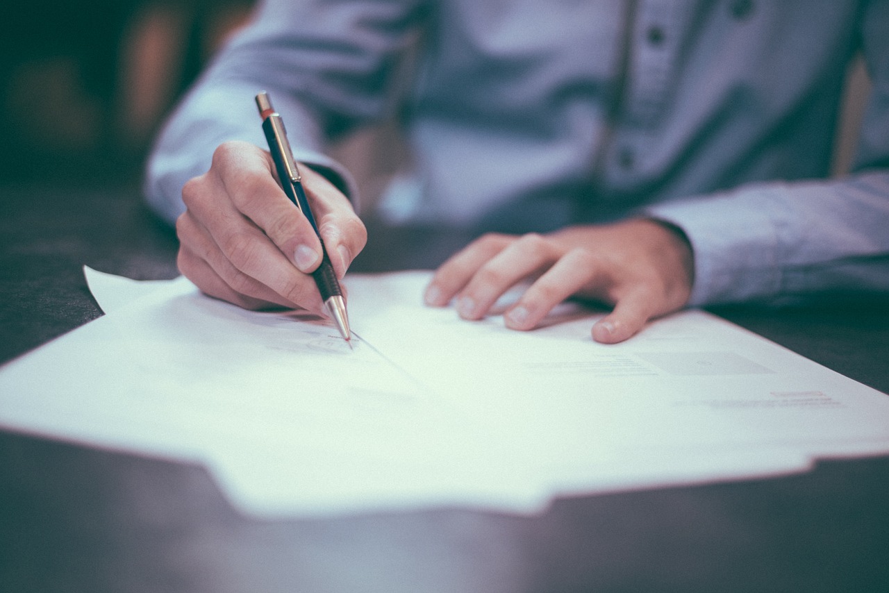 Firma de documento. Persona firmando un documento.