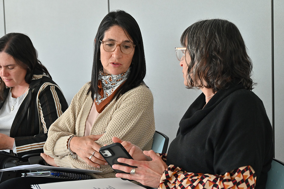 Fotografía de tres mujeres reunidas en una sala. Dos de ellas están conversando.