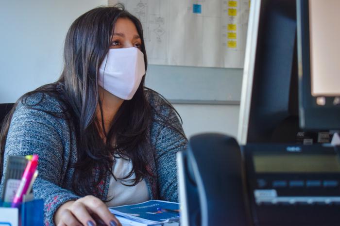 Foto de trabajadora en su computadora trabajando con barbijo 