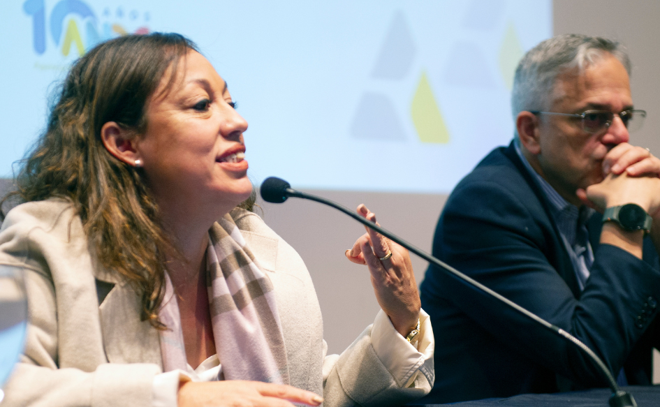 Ministra de Industria, Fernanda Cardona, habla haciendo un gesto con la mano (une el dedo índice con el pulgar). A su lado, la escucha el director de OPP, Rodrigo Arim, con ambas manos apoyadas en su mentón