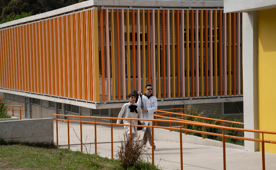 Un niño y un maestro caminan por el patio de la escuela Australia de Pajas Blancas