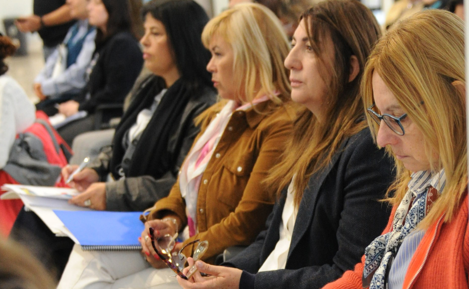 Cuatro mujeres observan la presentación de los datos del Monitor Educativo desde el público