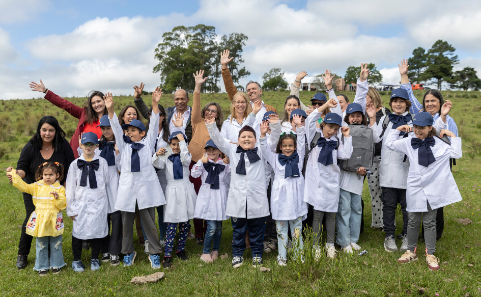 Presidente Yamandú Orsi saluda a la cámara junto a niños de la escuela rural n°44 de Sierras del Yerbal, y niños de escuelas rurales de la zona. Todos saludan a la cámara con la mano extendida hacia arriba 