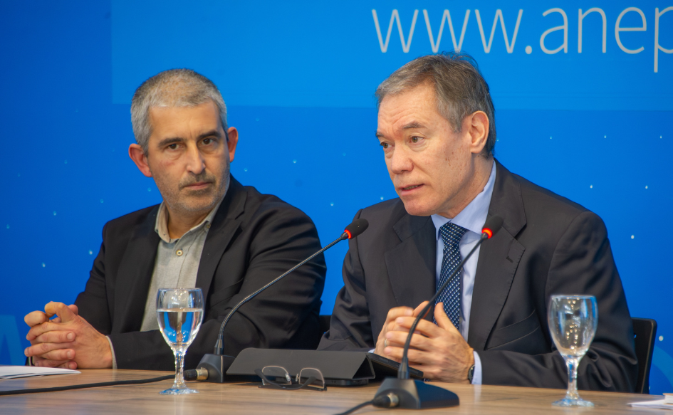 Subsecretario de Economía, Martín Vallcorba, habla en conferencia de prensa, juntando ambas manos. A su lado, el presidente de ANEP, Pablo Caggiani, lo escucha atentamente