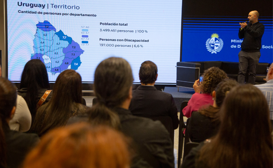 Director de Discapacidad, Federizo Lezama, señala un mapa político de Uruguay que contiene el porcentaje de población con discapacidad en cada departamento. La leyenda "Personas con discapacidad 197.000, 6,6%"
