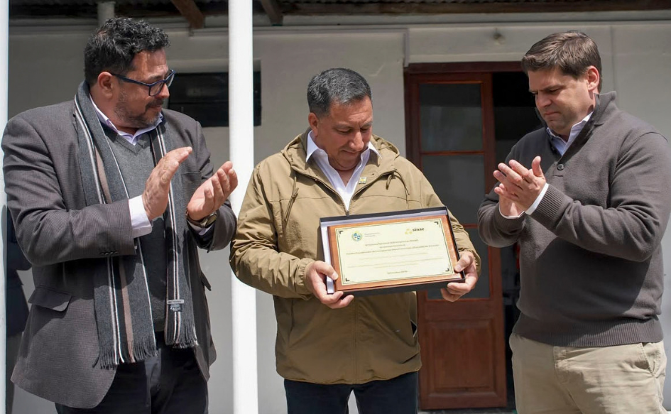 Responsable del Cecoed de Durazno sostiene una placa alusiva al 20° aniversario del centro. A su lado, lo aplauden el secretario de Presidencia, Alejandro Sánchez, y el intendente de Durazno, Felipe Algorta