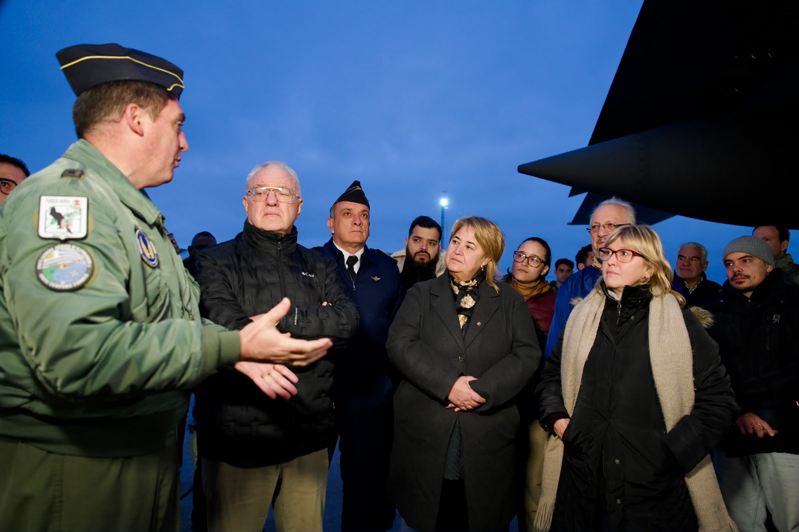 Funcionario de la Fuerza Aérea habla con los ministros de Relaciones Exteriores, Defensa Nacional y Salud Pública. Detrás de ellos, venezolanos que viven en Uruguay lo escuchan atentamente. En el fondo, parte del avión Hércules de la Fuerza Aérea