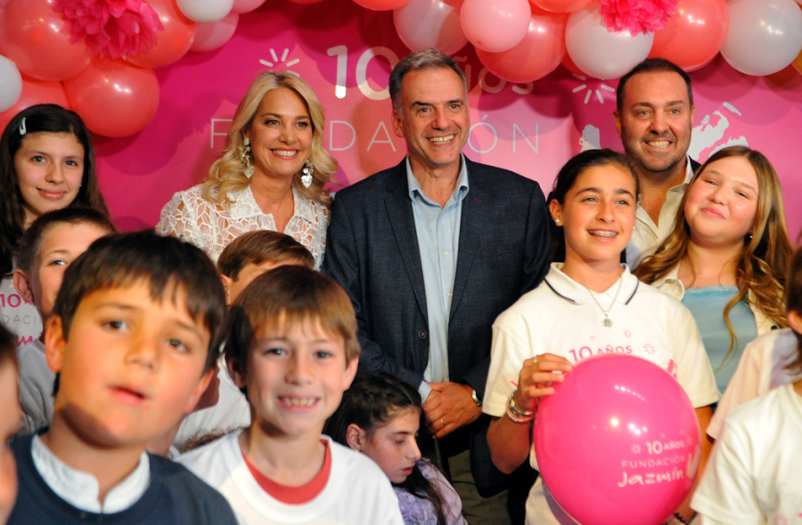 Presidente Yamandú Orsi junto a la directora de la Fundación Jazmín, rodeados de niños. En el fondo, globos rosados