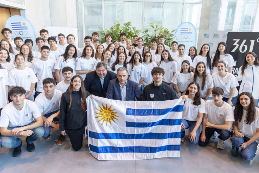 Presidente Orsi y delegación de deportistas juveniles posando con el pabellón nacional 