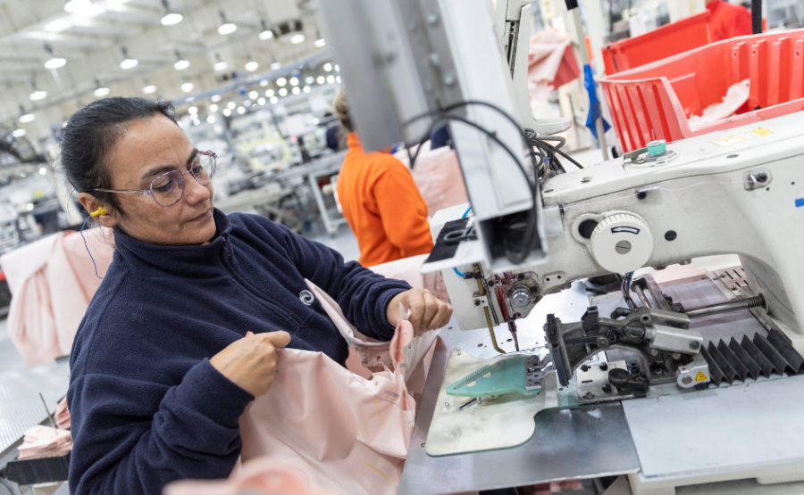 Mujer manipula una máquina de coser airbags en una planta industrial
