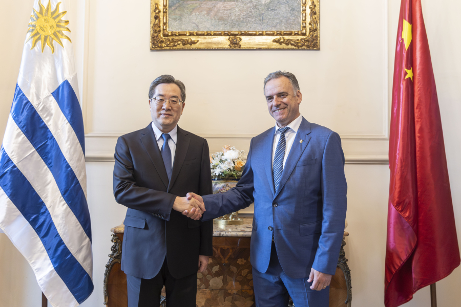Presidente Yamandú Orsi y el viceprimer ministro Ding Xuexiang se saludan con apretón de manos. En el fondo, las bandera