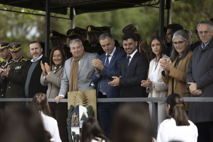 El presidente Yamandú Orsi, parado, aplaude a un grupo de personas que desfilan en Sarandí Grande. A su lado, el intende