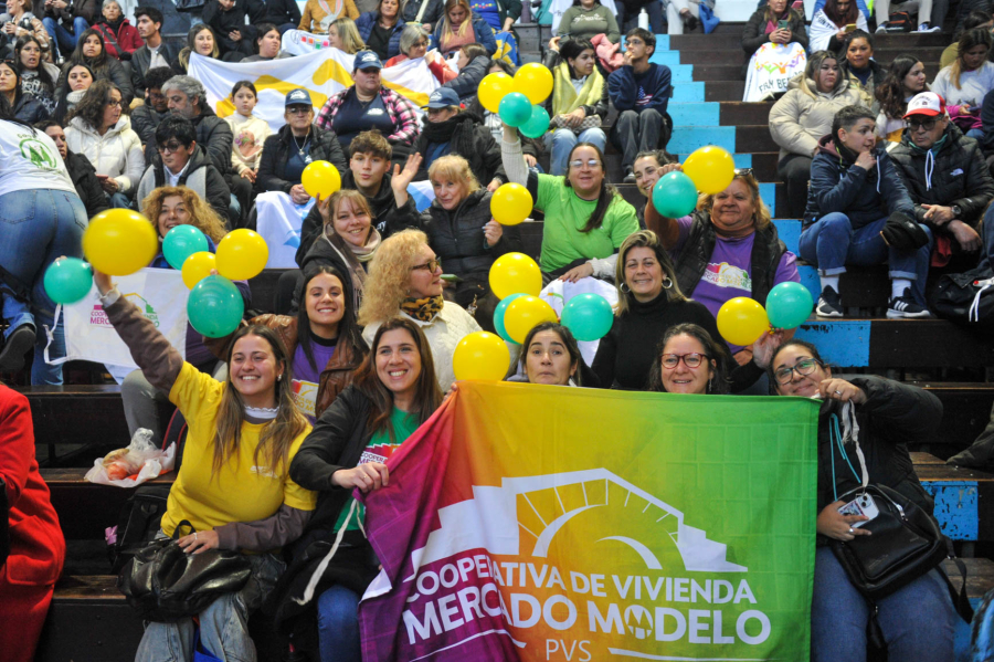 Integrantes de una cooperativa de viviendas esperan un sorteo con globos y banderas