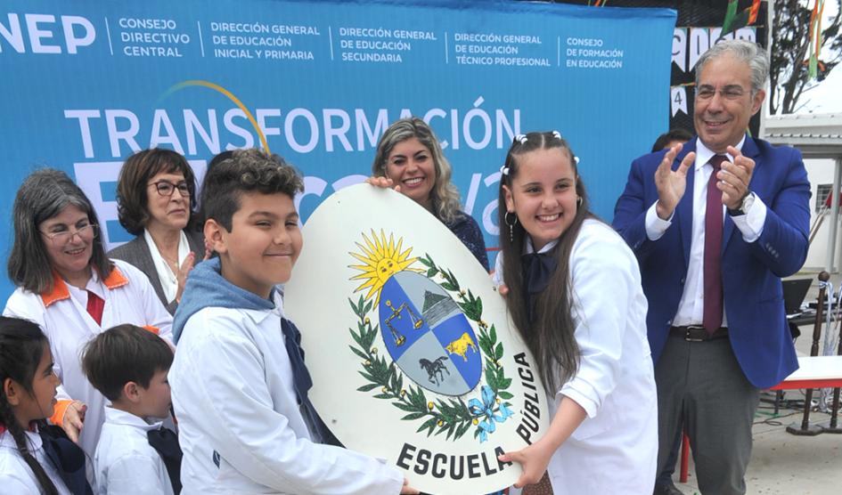 Presidente de la ANEP, Robert Silva, junto a escolares que sostienen un escudo nacional Presidente de la ANEP, Robert Silva, junto a escolares que sostienen un escudo nacional