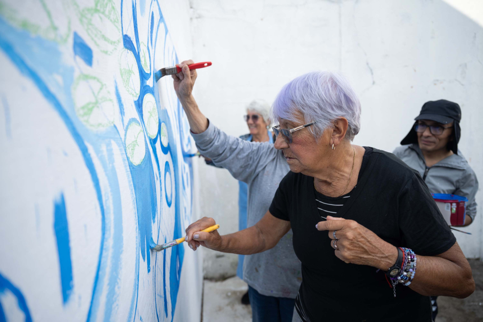 Señora de unos 70 años pinta un mural