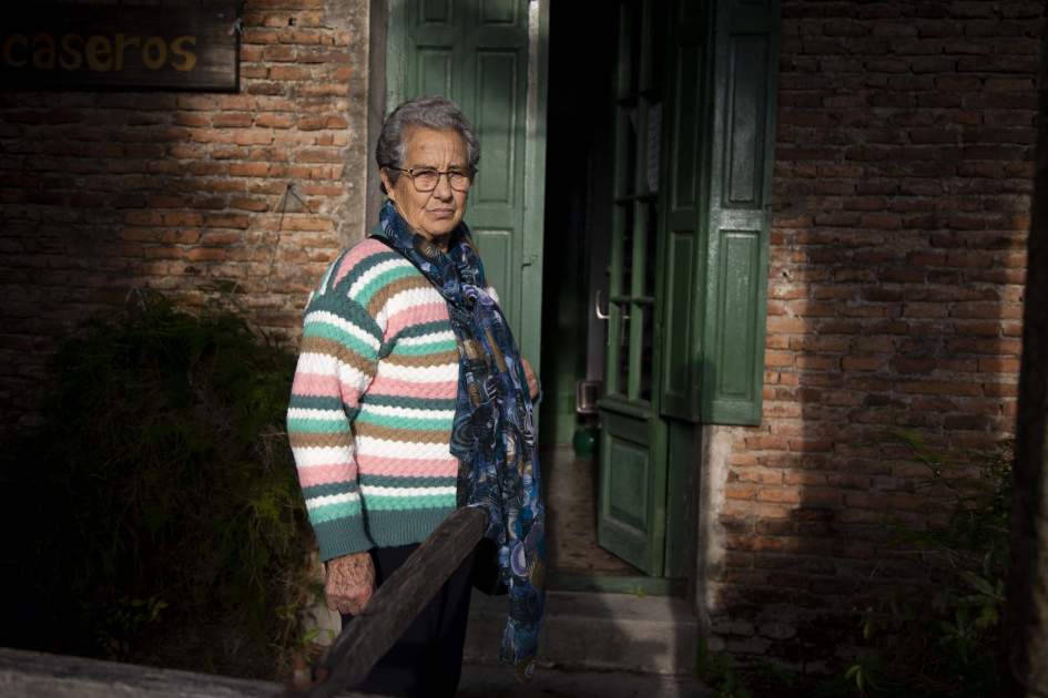 Señora de unos 80 años frente a la puerta de su casa