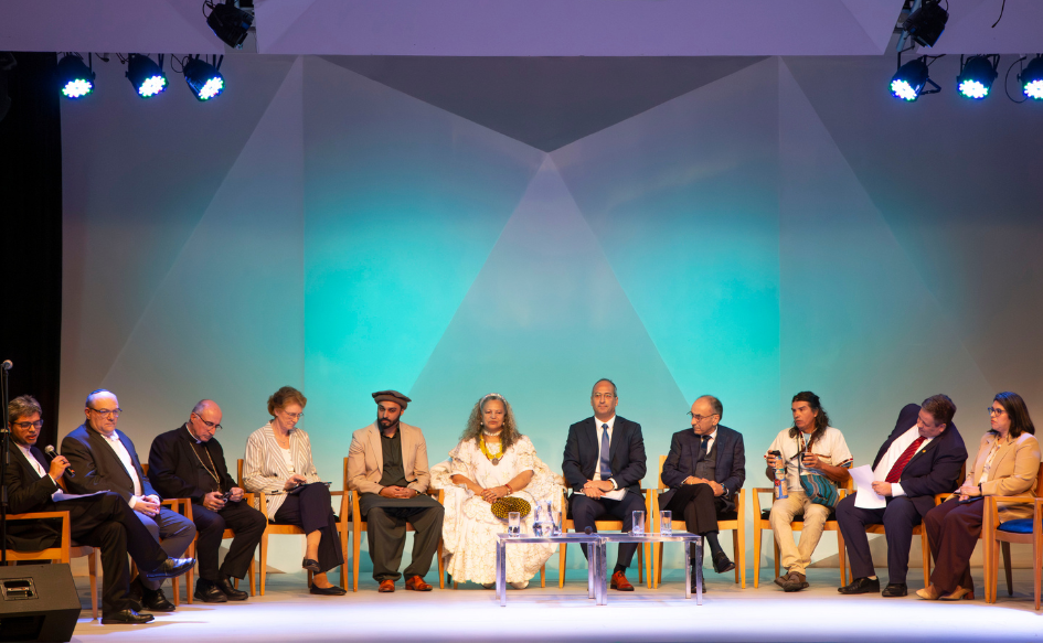 Líderes de 10 comunidades religiosas sentados en el escenario de la sala Vaz Ferreira