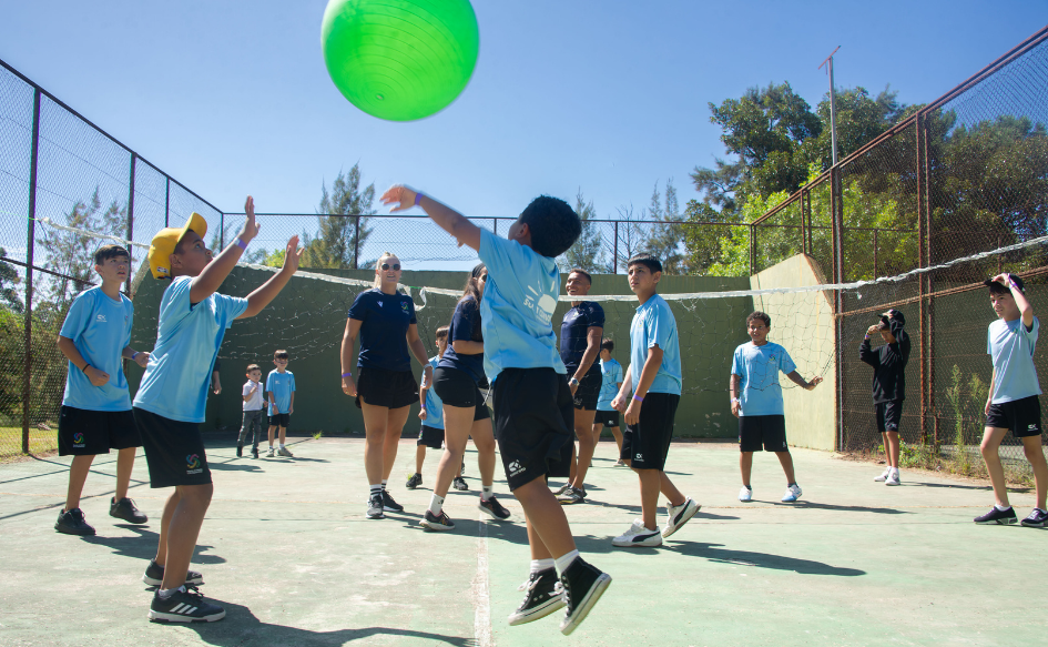 Niños juegan al voleyball con una pelota de grandes dimensiones