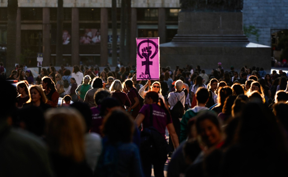 Extensión del plazo para presentar propuestas sobre planes de género y vida libre de violencia hacia las mujeres Cientos de mujeres congregadas en la plaza Independencia, durante una marcha del 8M. En el centro de la imagen, una de ellas levanta un cartel con una imagen que mezcla el símbolo de Venus con un puño levantado