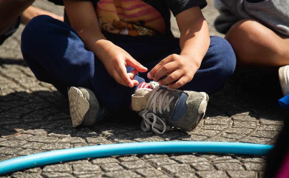 Plano de las piernas de un niño sentado en el piso. 