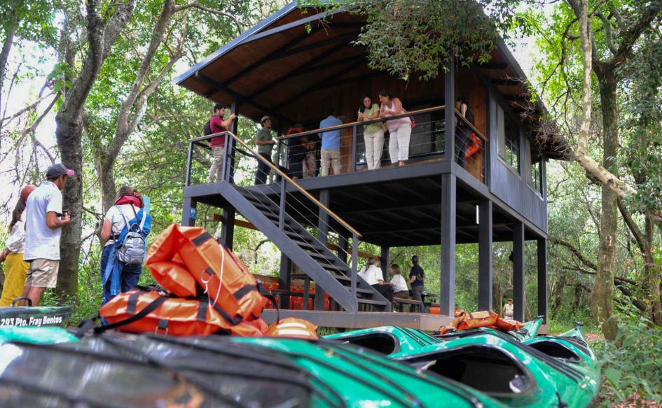 Turismo procura ampliar cantidad de destinos inteligentes en todo el país Turistas conversan y toman fotografías en una cabaña. Delante, dos botes