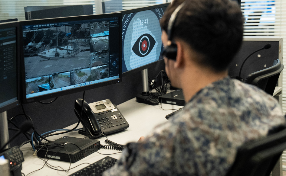 Funcionario del Centro de Comando Unificado observa un monitor, con auriculares puestos