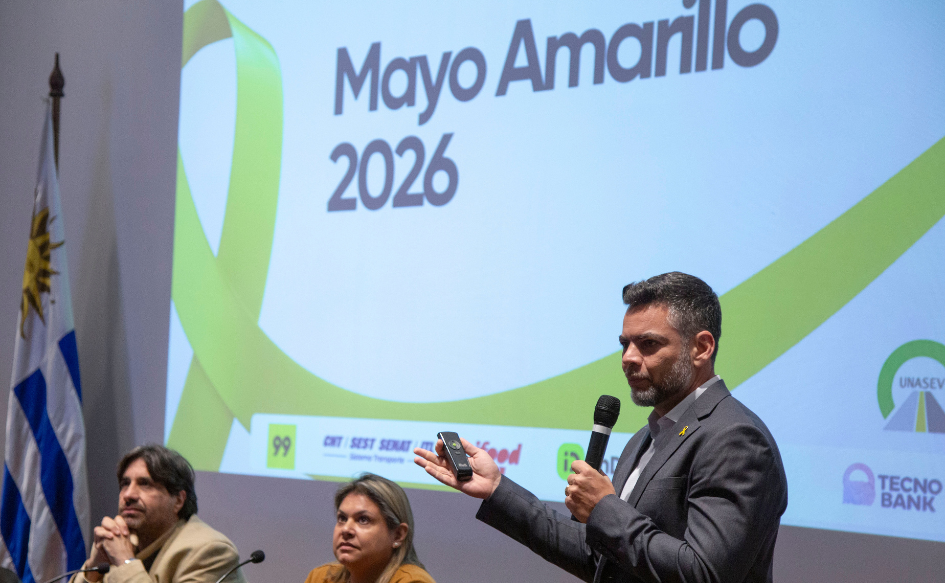 Director ejecutivo del Observatorio Nacional de Seguridad Vial de Brasil, Paulo Guimaraes, habla de pie y señala una pantalla que dice "Mayo Amarillo 2026". Observa la presentación el presidente de Unasev, Marcelo Metediera