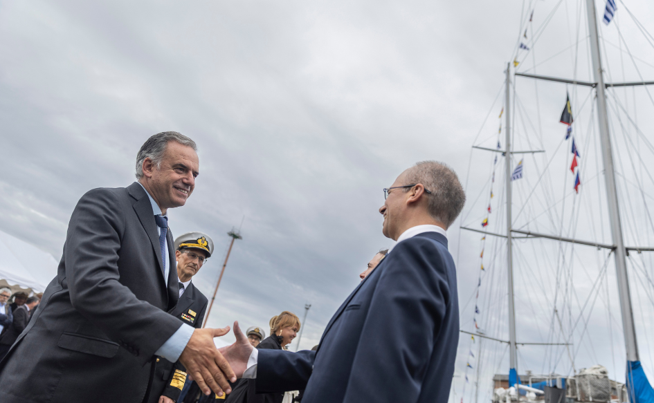 Presidente Yamandú Orsi saluda al comandante del Capitán Miranda. De fondo, el velero. 