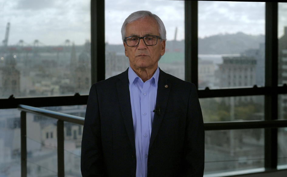Ministro de Trabajo, Juan Castillo, de pie. De fondo, imágenes de Ciudad Vieja y el puerto de Montevideo