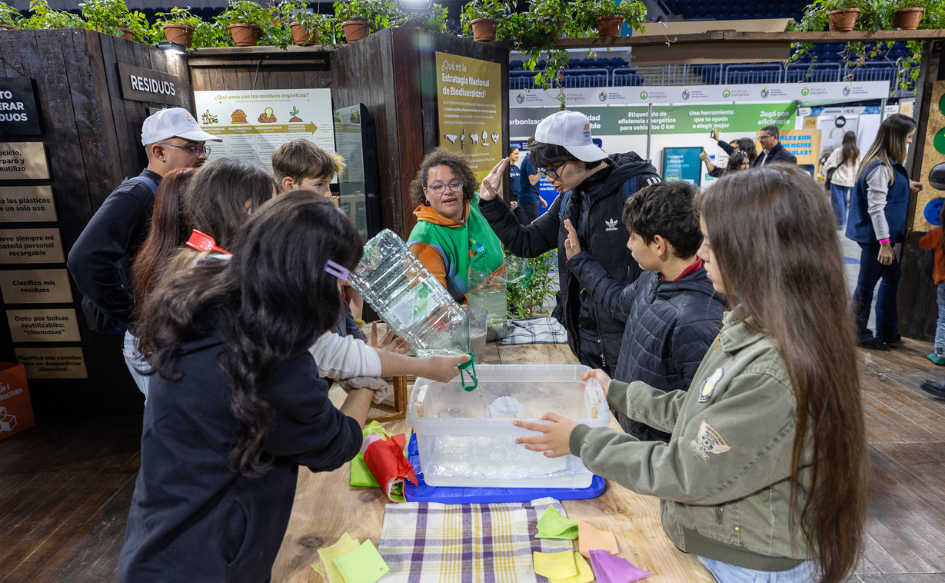 Comenzó la Expo Uruguay Sostenible, con más de 200 stands y énfasis en educación ambiental Una decena de adolescentes de unos 13 años de edad están parados alrededor de una mesa. Una de ellas sostiene un bidón de plástico. Una adulta, en la cabecera de la mesa, les habla.
