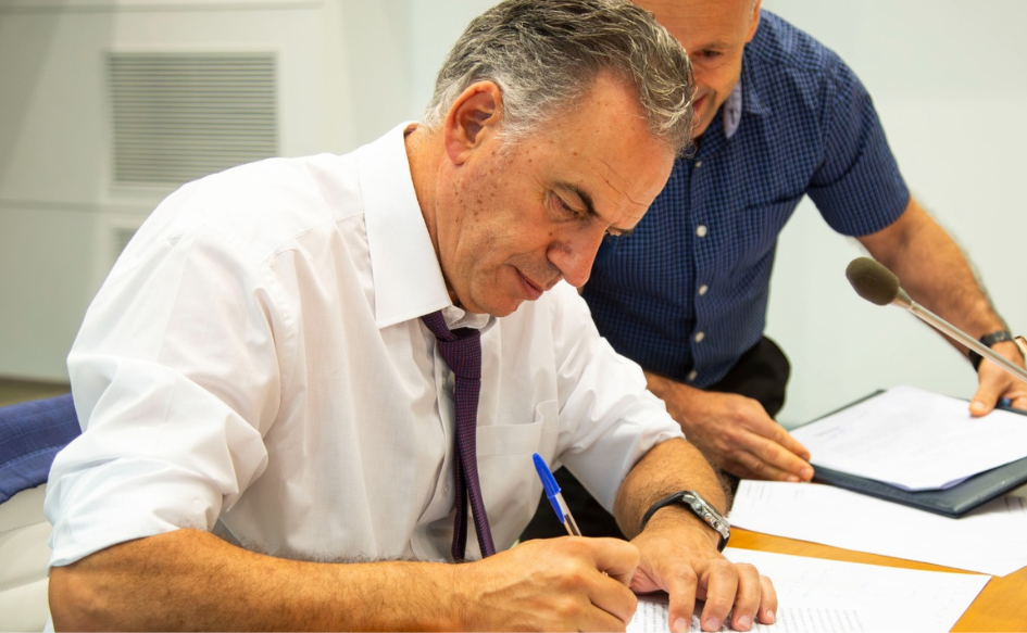 Presidente Yamandú Orsi, de camisa y corbata, firma una resolución