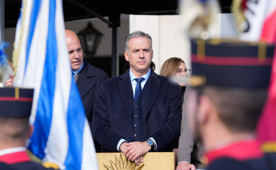 Presidente Orsi ratificó rumbo económico del Gobierno Presidente Yamandú Orsi, de pie, con una mano apoyada arriba de la otra. Delante de él, el pabellón nacional