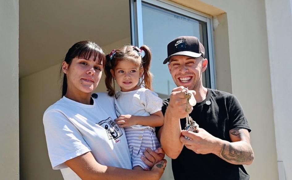 Vivir el barrio: cuando el Estado llega Adultos de unos 20 años sonríen y muestran una llave. En medio, una niña de unos tres años.