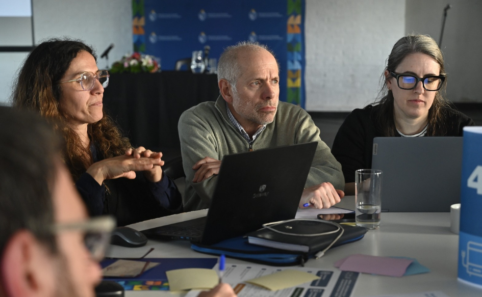 Área metropolitana: Gobierno nacional e intendencias articulan estrategia común. Foto: MVOT Tres miembros de la Comisión Asesora de Ordenamiento Territorial, sentados alrededor de una mesa, con una notebook abierta