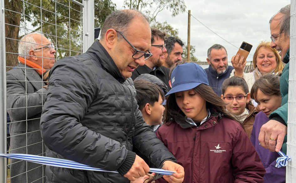 Familias de Coronilla de Caraguatá, en Rivera, acceden al servicio de agua potable Vicepresidente de OSE, Guillermo Caraballo, corta una cinta de inauguración junto a una niña en Coronilla de Caraguatá, Rivera. Detrás de ellos, varias personas observan alegres la situación