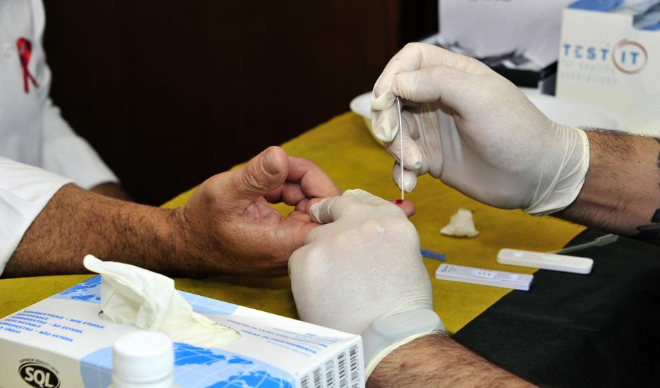 Técnico realizando un test de sangre en el dedo a una persona Técnico realizando un test de sangre en el dedo a una persona