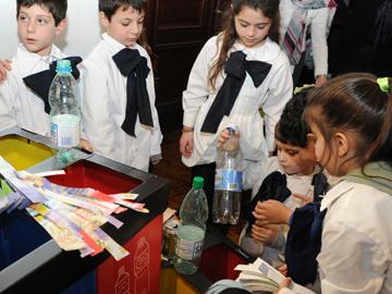Niños depositando residuos en papelera de reciclaje Niños depositando residuos en papelera de reciclaje