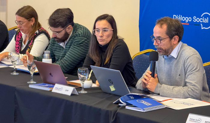Coordinador de la Comisión Ejecutiva del Diálogo Social diserta con micrófono en mano en mesa.