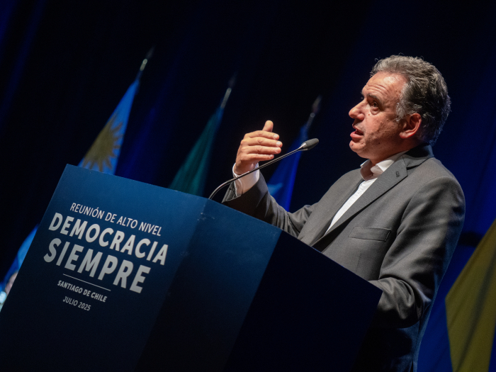 Presidente Yamandú Orsi diserta en un atril azul con logo “Democracia Siempre” y micrófono.