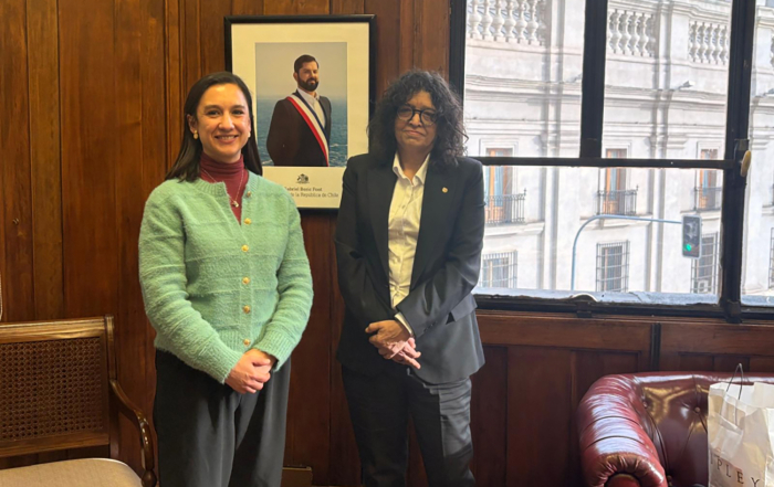 Secretarias de Derechos Humanos de Uruguay y Chile posan frente a cámara sonrientes en una oficina.
