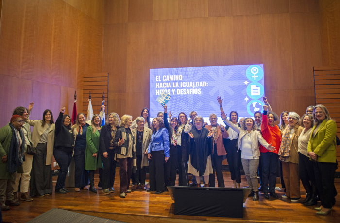Autoridades y participantes del evento parados en escenario del auditorio posan sonrientes.