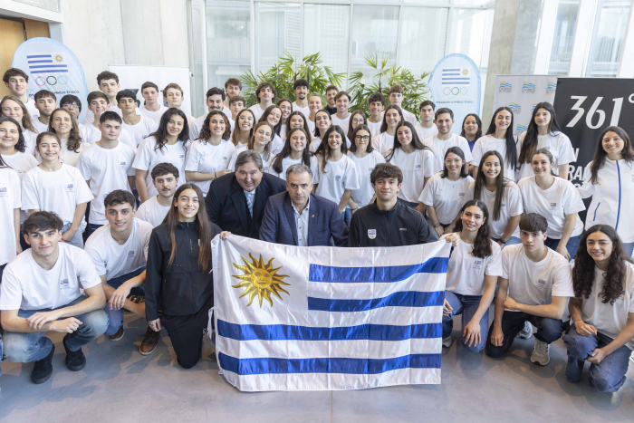 Presidente Orsi junto a delegación de atletas uruguayos posan frente a cámara con el pabellón.