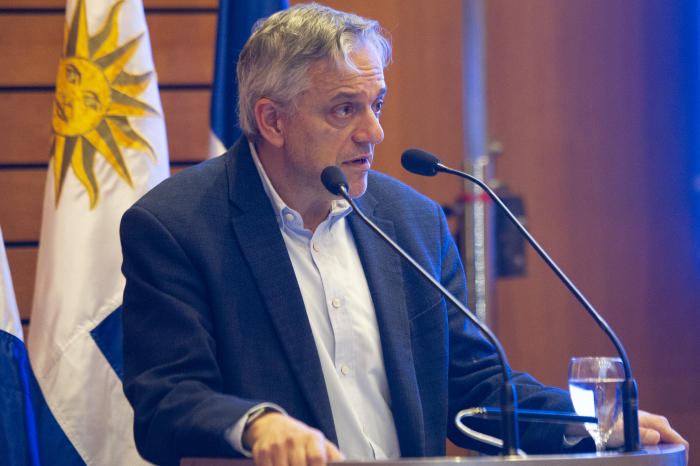 Director de OPP diserta parado en atril con micrófono en escenario del auditorio de Presidencia.