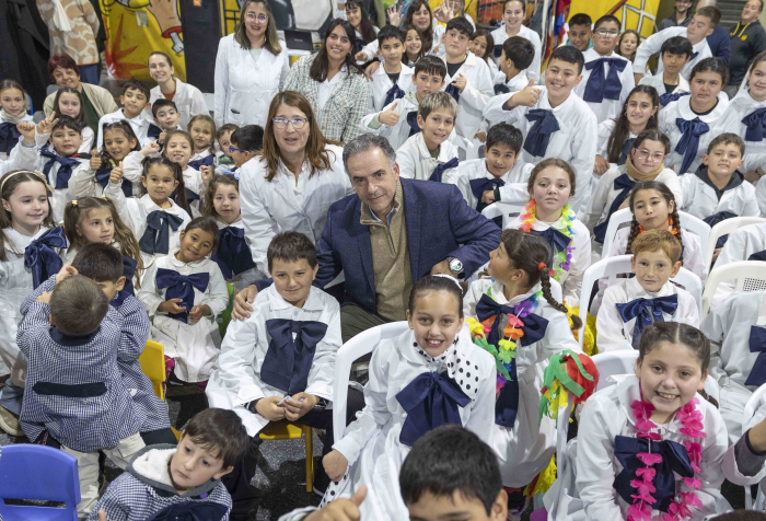 Presidente Orsi junto a un grupo de escolares con túnicas blancas posa sonriente frente a cámara
